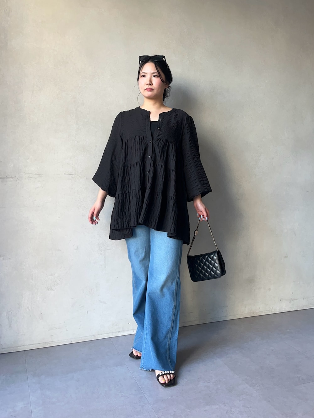 ブルー系のデニムパンツ、ブラック系のトートバッグ、ブラック系のキャミソールを着用したレディースの春コーディネートの2枚目の写真