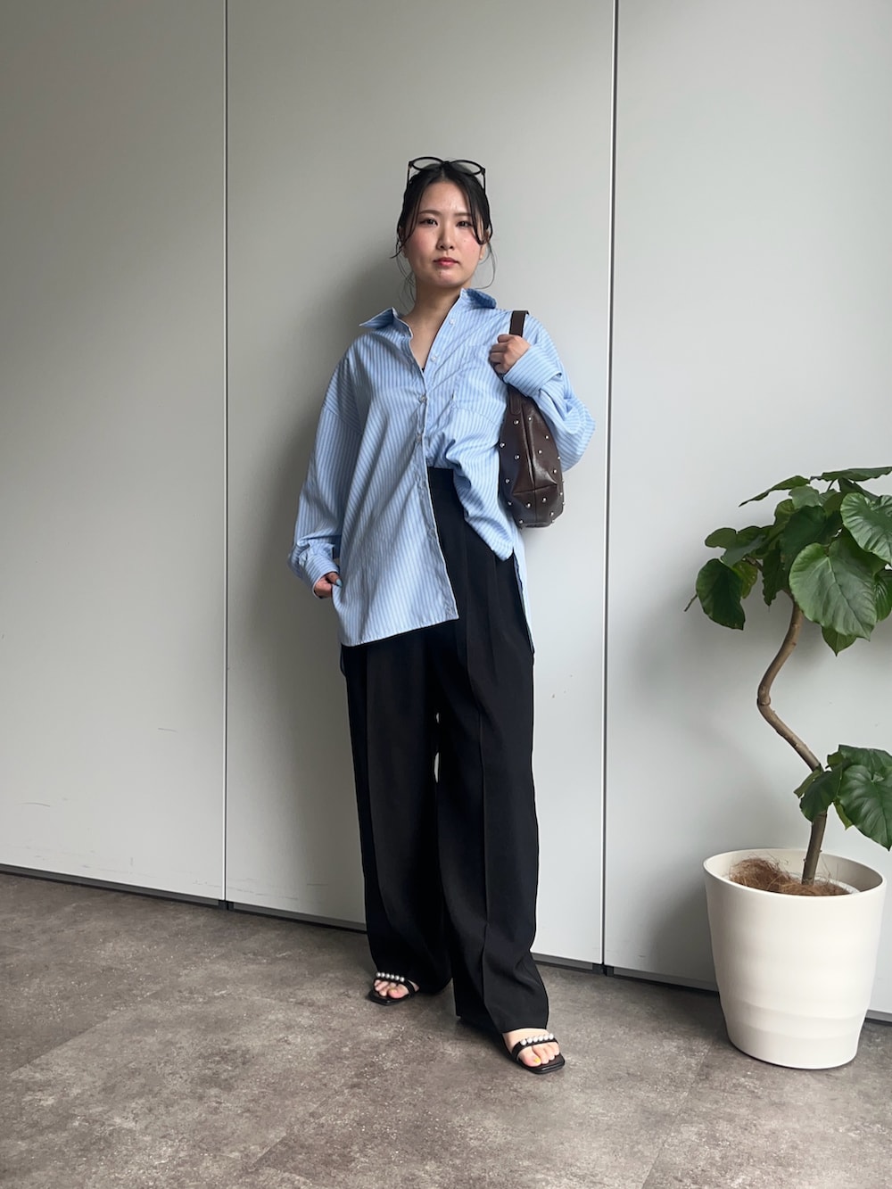 ブルー系のシャツ/ブラウス、ブラック系のサンダル、ブラック系のスラックスを着用したレディースの春コーディネートの2枚目の写真