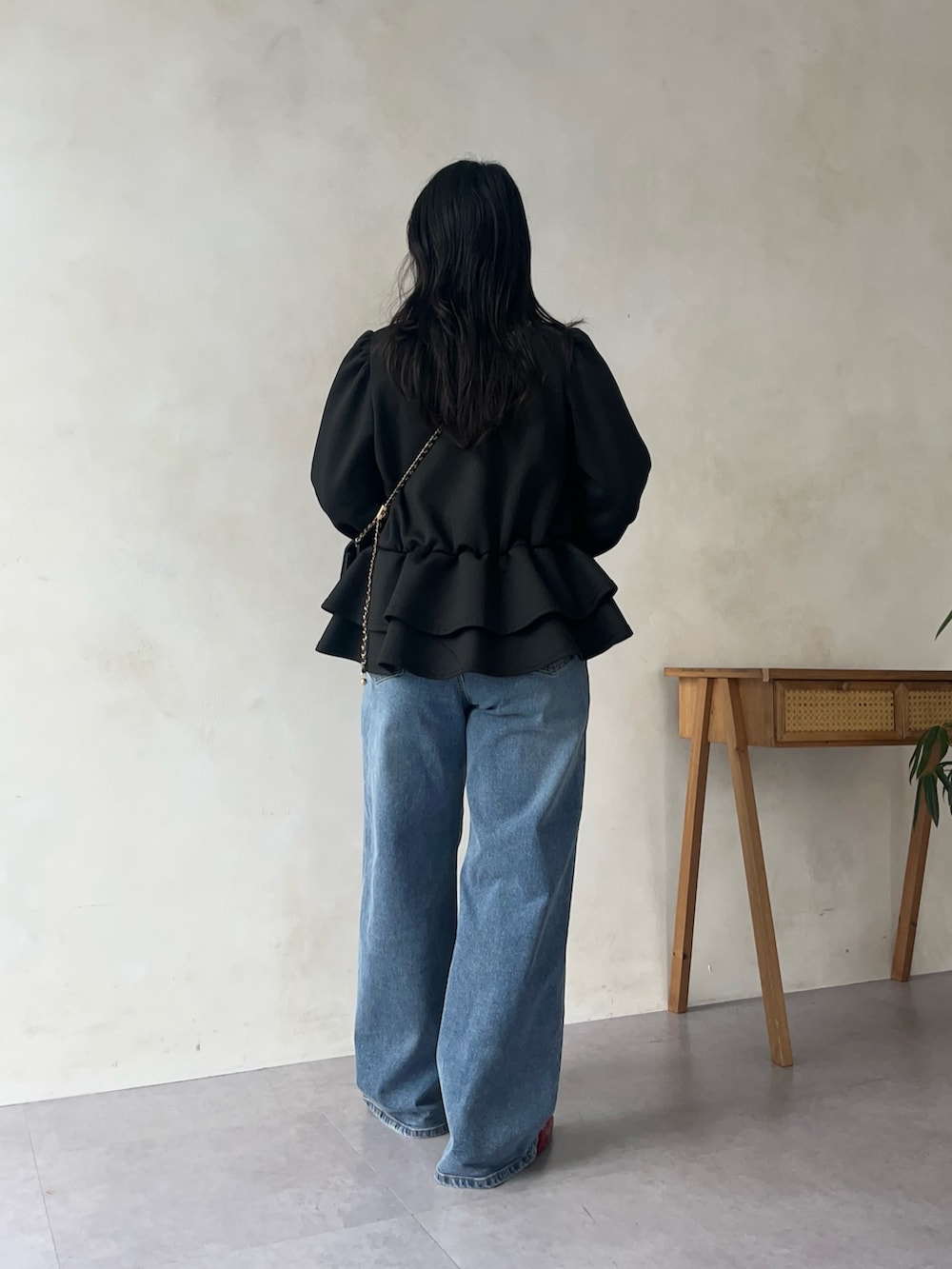 ブラック系のスウェット、ブルー系のデニムパンツ、レッド系のパンプスを着用したレディースの秋コーディネートの3枚目の写真