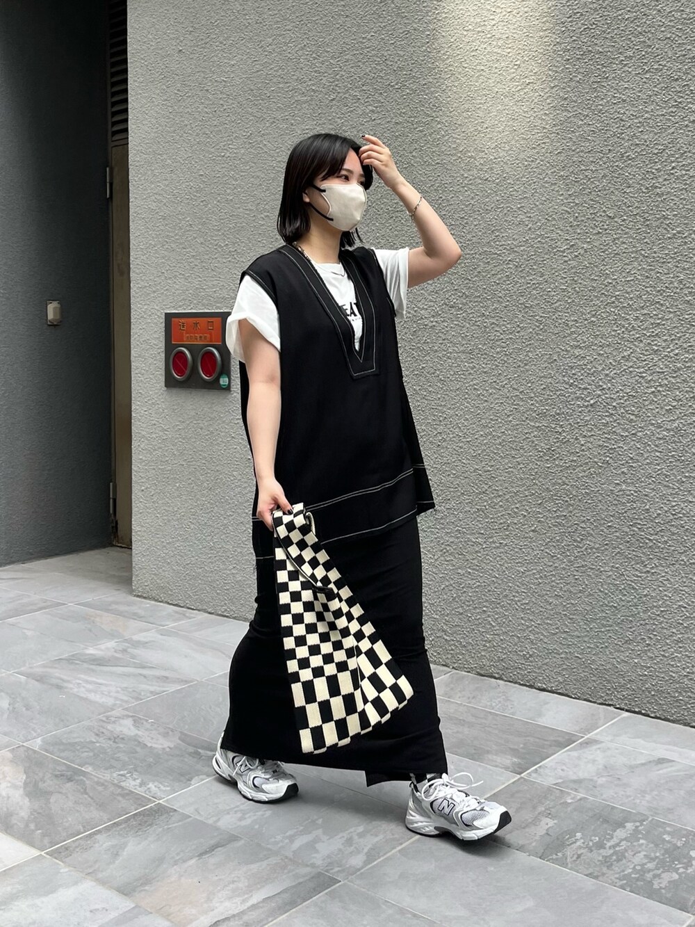 ブラック系のベスト、ブラック系のスカート、ホワイト系のTシャツ/カットソーを着用したレディースの春コーディネートの2枚目の写真