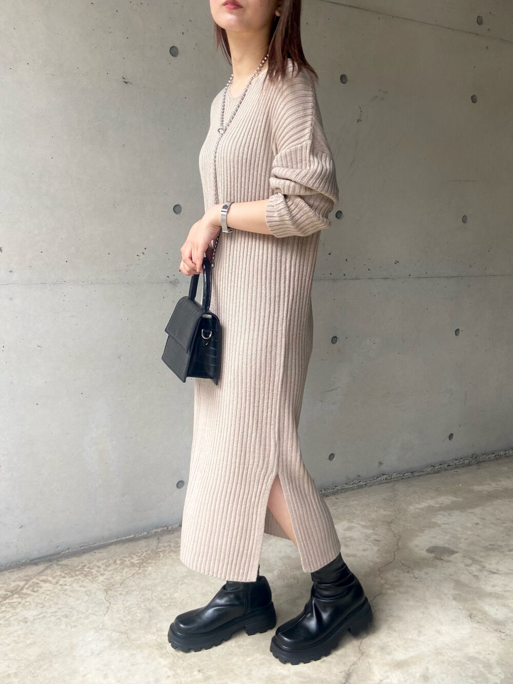 ブラック系のショルダーバッグ、ベージュ系のワンピース、ブラック系のブーツを着用したレディースの秋コーディネートの2枚目の写真