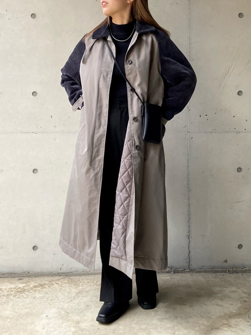 グレー系のステンカラーコート、ブラック系のショルダーバッグ、ブラック系のニット/セーターを着用したレディースの秋コーディネートの3枚目の写真