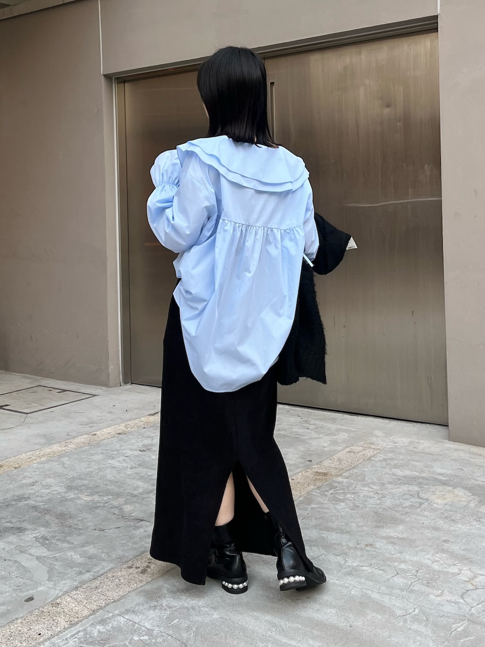 ブラック系のスカート、ブラック系のブーツ、ブラック系のショルダーバッグを着用したレディースの冬コーディネートの3枚目の写真