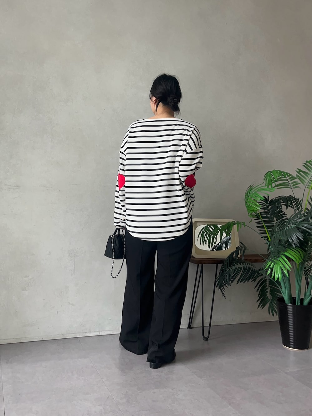 ブラック系のスラックス、ブラック系のショルダーバッグ、ホワイト系のTシャツ/カットソーを着用したレディースの夏コーディネートの3枚目の写真