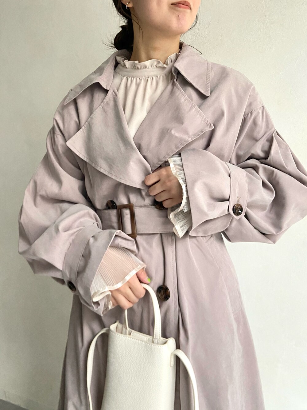 ホワイト系のショルダーバッグ、ベージュ系のトレンチコート、ベージュ系のシャツ/ブラウスを着用したレディースの冬コーディネートの3枚目の写真