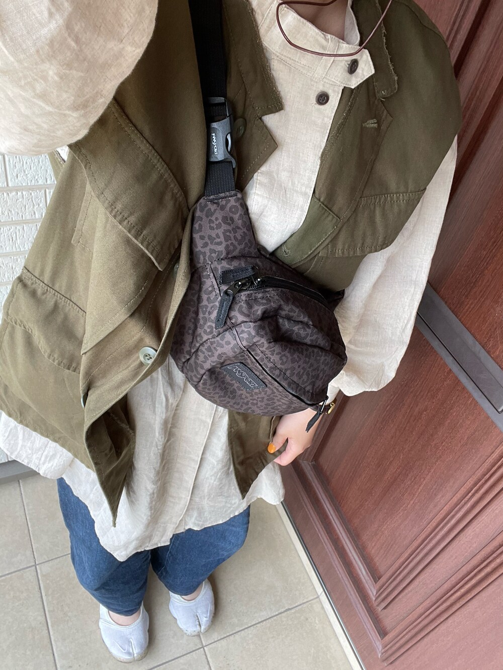 ベージュ系のシャツワンピース、ブルー系のデニムパンツ、ブラウン系のサンダルを着用したレディースの春コーディネートの2枚目の写真