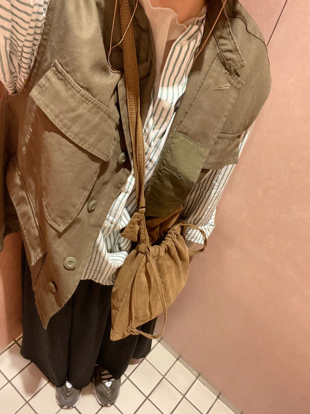 グリーン系のナイロンジャケット、ブラック系のスニーカー、ブラウン系のショルダーバッグを着用したレディースの春コーディネートの2枚目の写真