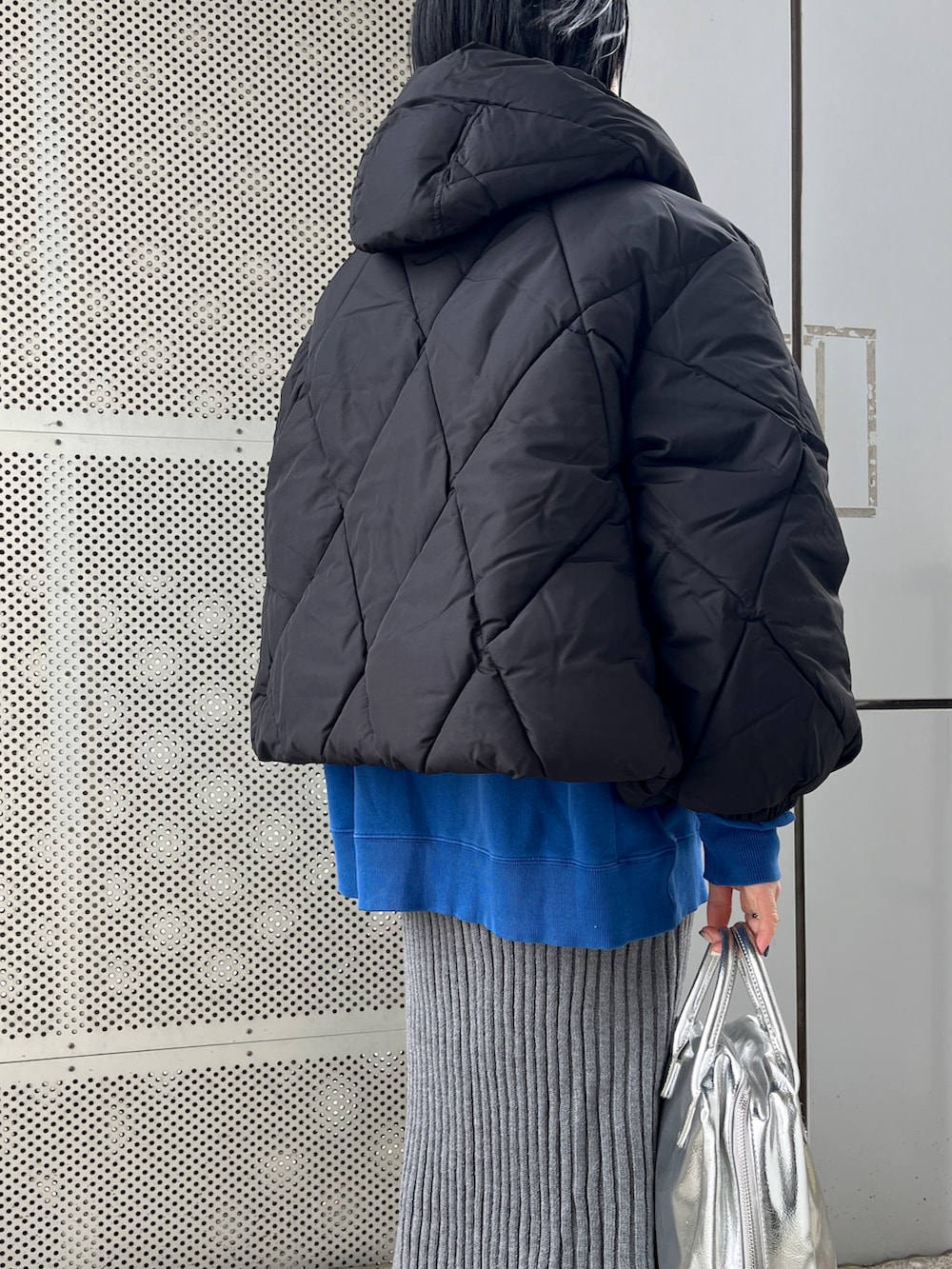 シルバー系のボストンバッグ、ブラック系のブーツ、ブラック系のジャケット/アウターを着用したレディースの秋コーディネートの2枚目の写真