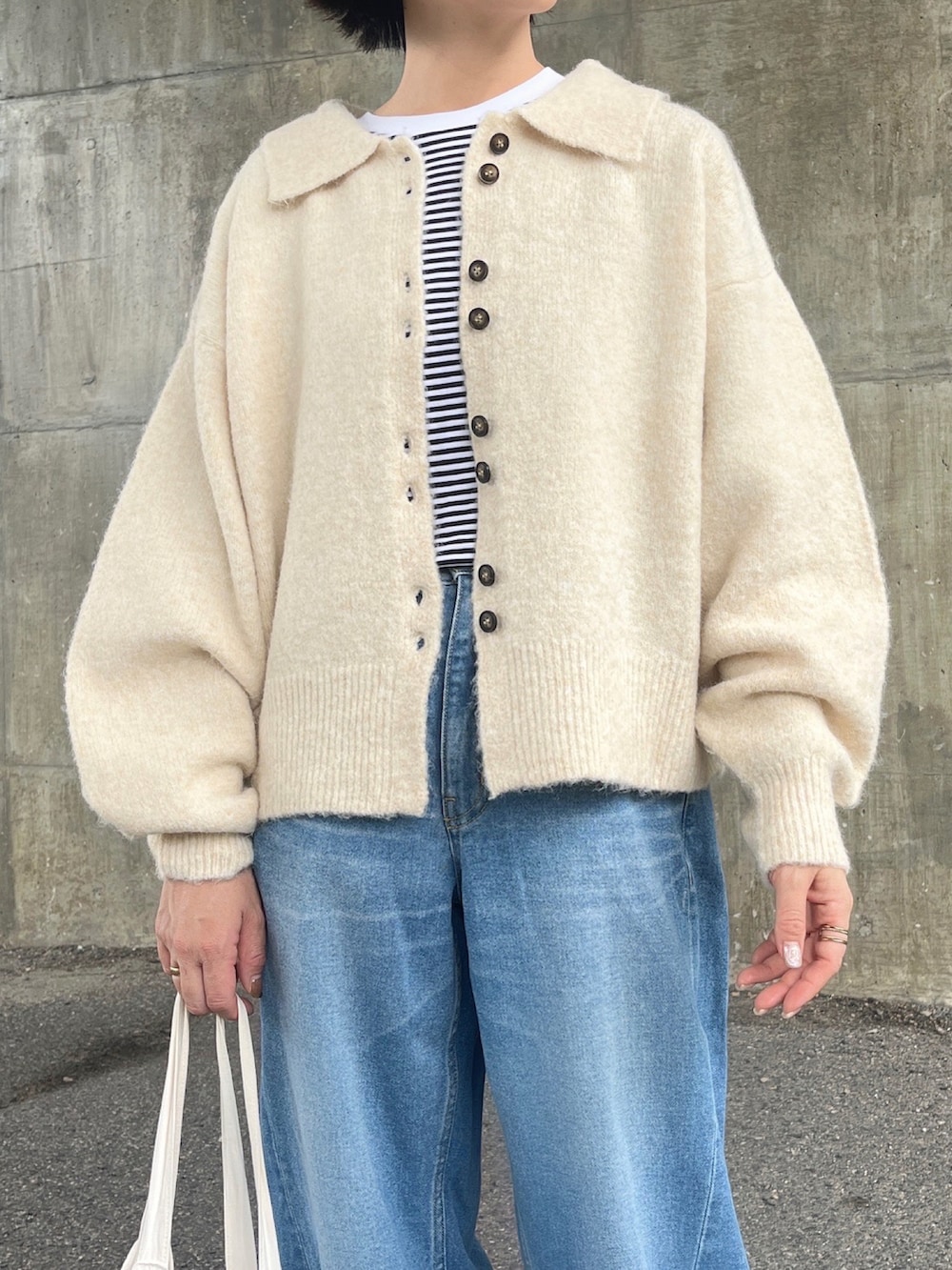 ホワイト系のカーディガン/ボレロ、ブルー系のデニムパンツ、ブルー系のキャップを着用したレディースの秋コーディネートの2枚目の写真