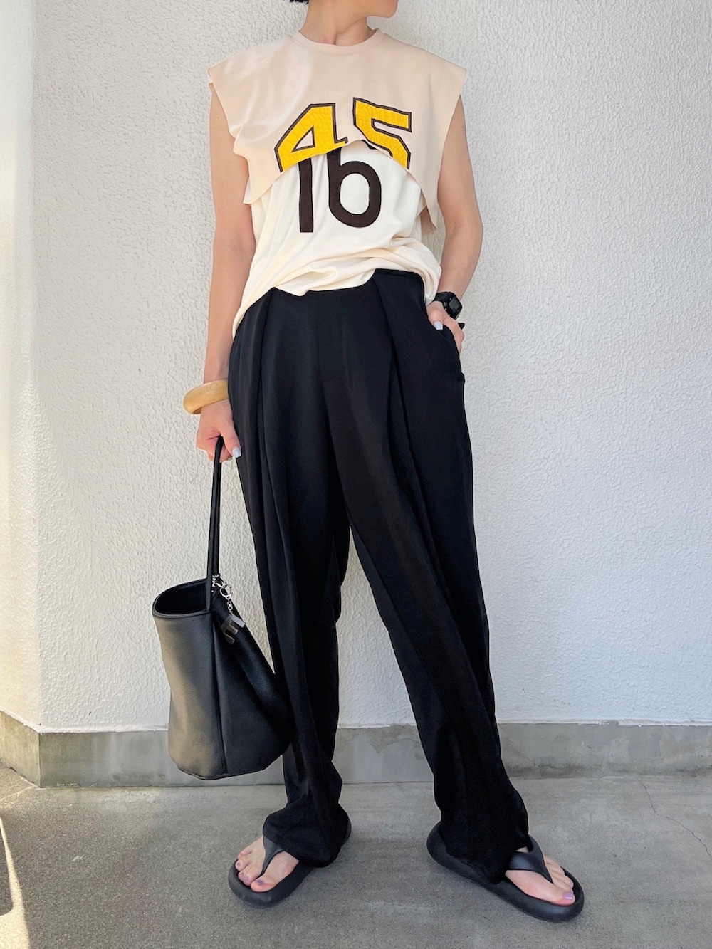 ブラック系のスラックス、ブラック系のサンダル、その他のTシャツ/カットソーを着用したレディースの夏コーディネートの2枚目の写真