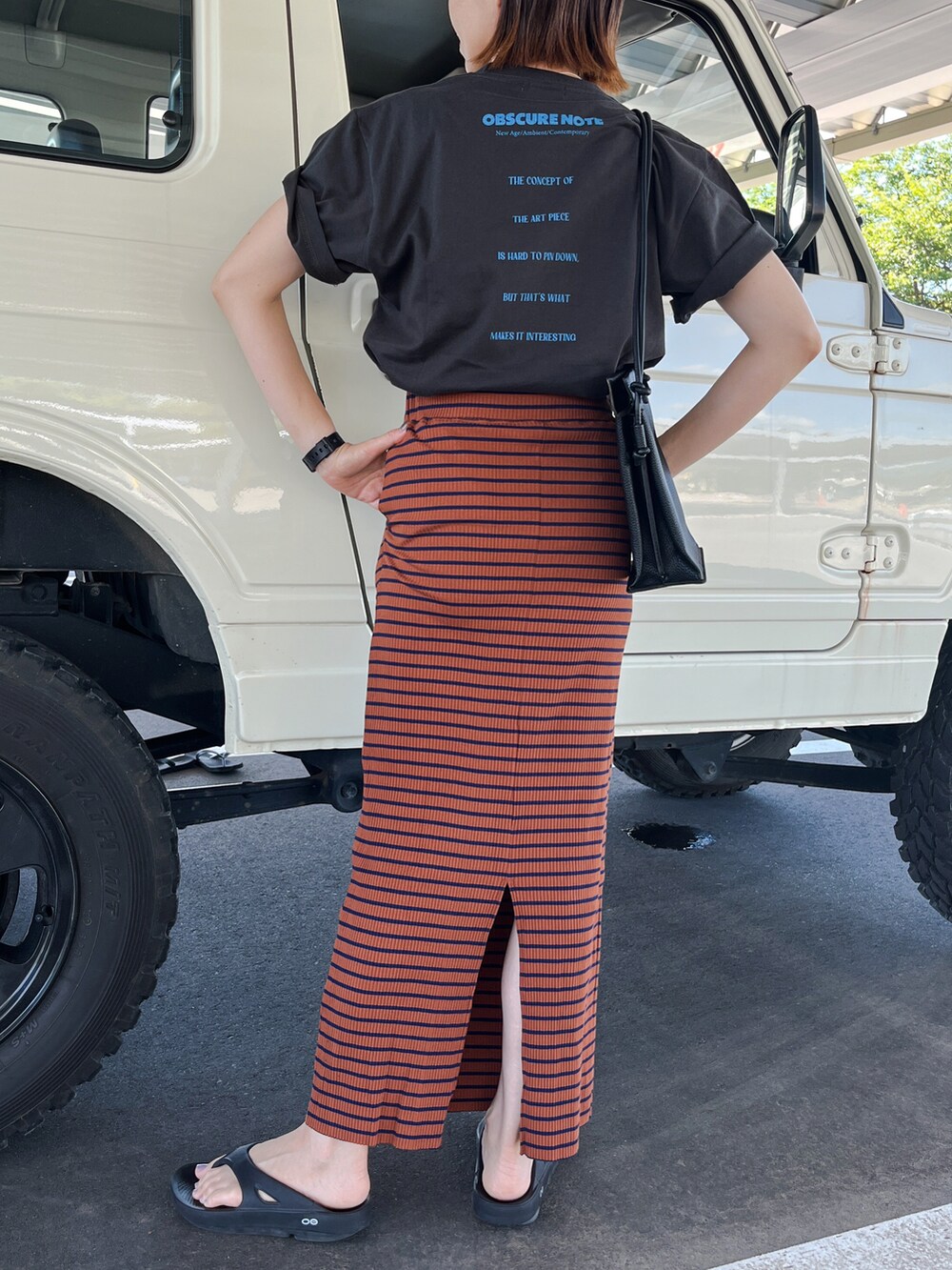 ブラック系のTシャツ/カットソー、ブラウン系のスカート、ブラック系のサンダルを着用したレディースの夏コーディネートの2枚目の写真