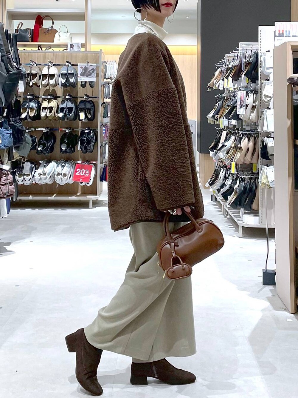 ブラウン系のハンドバッグ、ベージュ系のサロペット/オーバーオール、ホワイト系のニット/セーターを着用したレディースの秋コーディネートの6枚目の写真