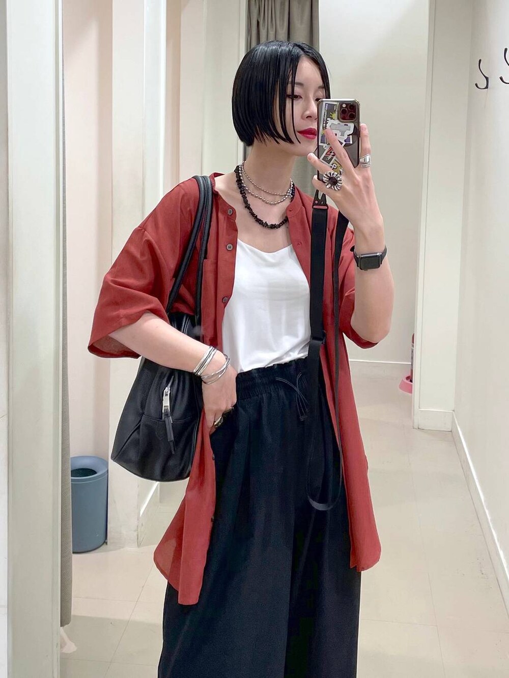 ブラック系のショルダーバッグ、ブラック系のその他パンツ、オレンジ系のシャツ/ブラウスを着用したレディースの夏コーディネートの2枚目の写真