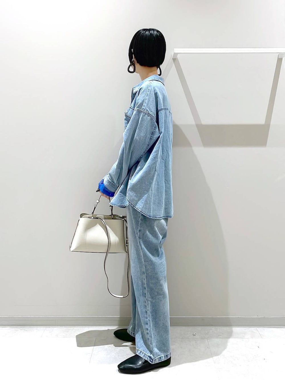 ブラック系のその他シューズ、ブルー系のデニムパンツ、ベージュ系のショルダーバッグを着用したレディースの春コーディネートの4枚目の写真