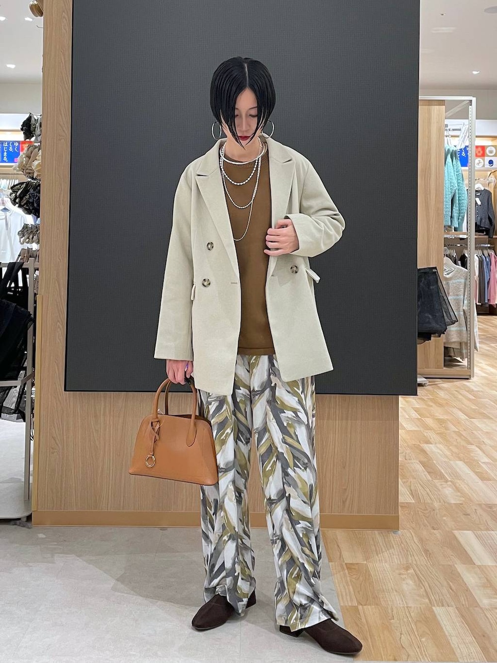 ブラウン系のショルダーバッグ、ブラウン系のニット/セーター、ブラウン系のブーツを着用したレディースの冬コーディネートの2枚目の写真