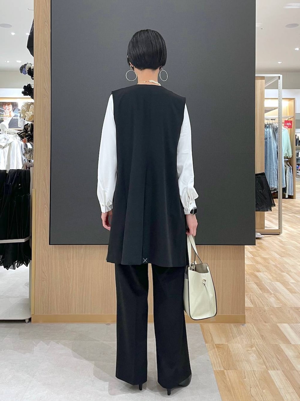 ホワイト系のショルダーバッグ、ブラック系のパンプス、ブラック系のスラックスを着用したレディースの冬コーディネートの3枚目の写真