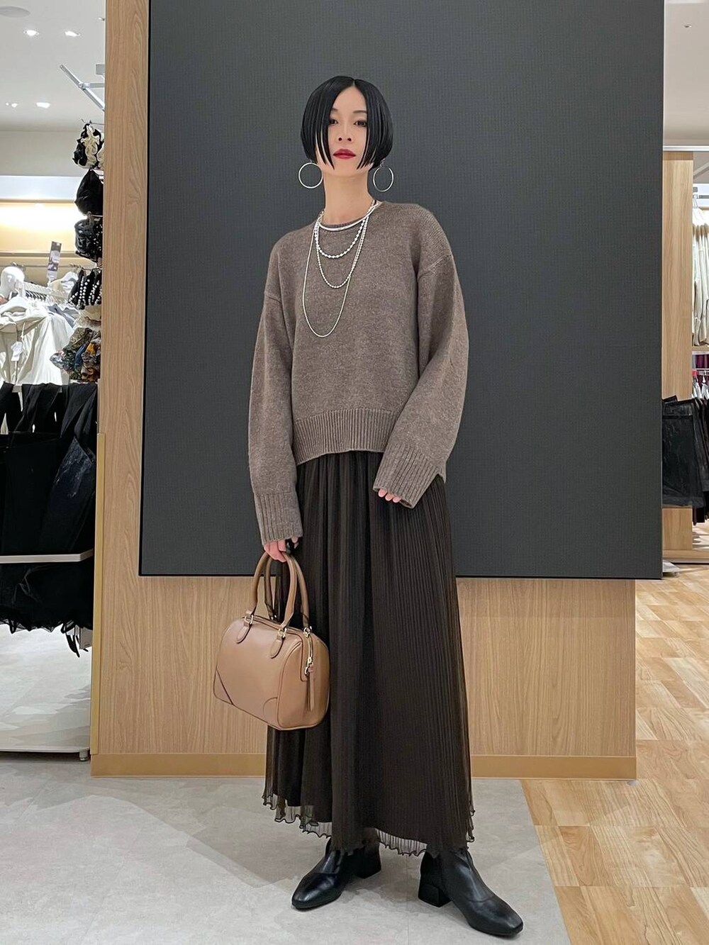 ベージュ系のボストンバッグ、ブラック系のブーツ、シルバー系のネックレスを着用したレディースの冬コーディネートの2枚目の写真