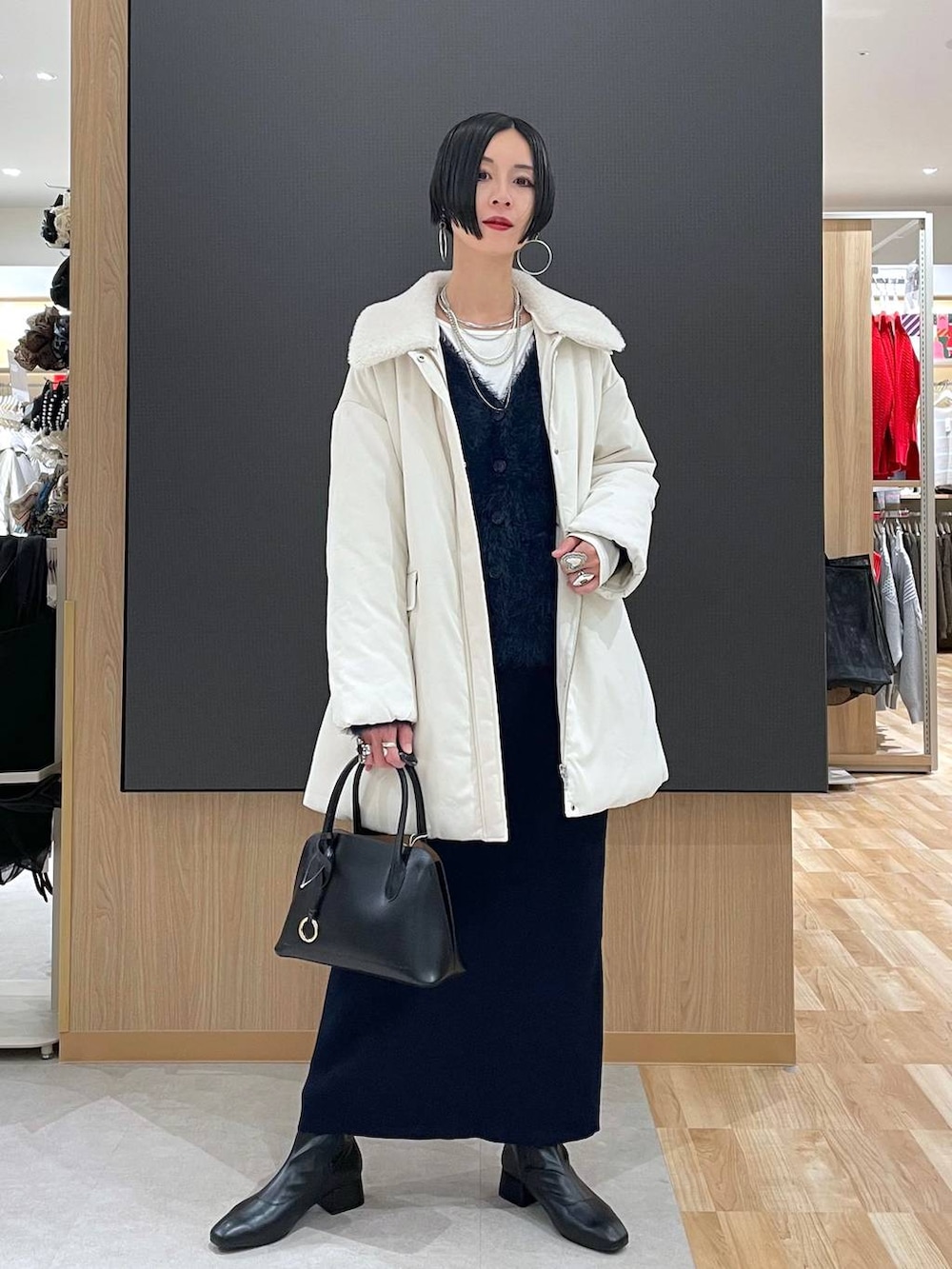 ブラック系のショルダーバッグ、ブルー系のワンピース、ブラック系のブーツを着用したレディースの冬コーディネートの2枚目の写真