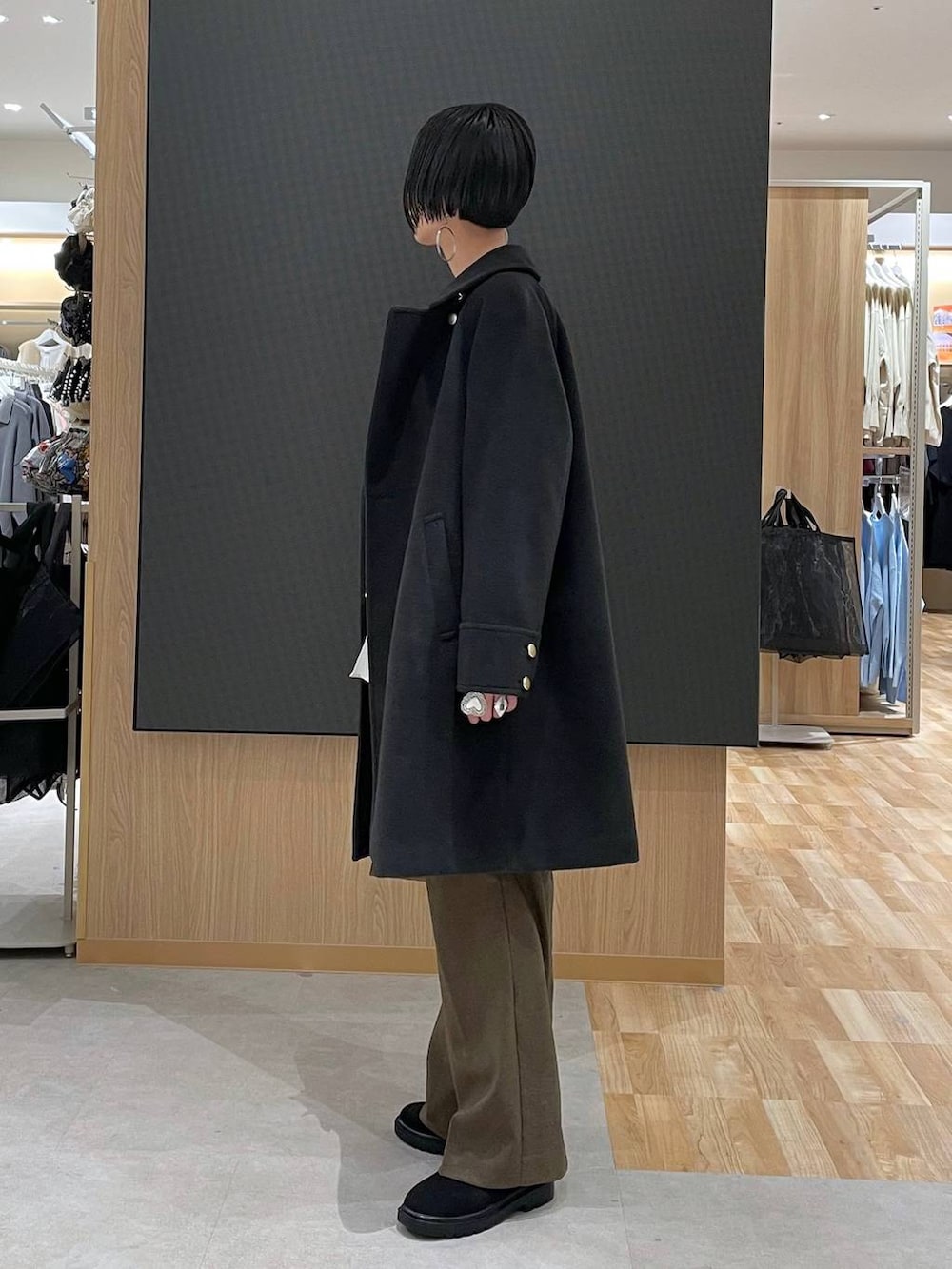 ブラック系のチェスターコート、ホワイト系のニット/セーター、ブラウン系のその他パンツを着用したレディースの冬コーディネートの4枚目の写真