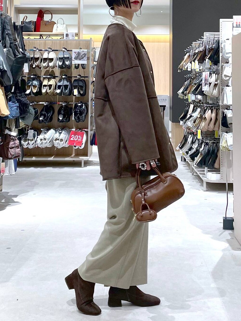 ブラウン系のハンドバッグ、ベージュ系のサロペット/オーバーオール、ホワイト系のニット/セーターを着用したレディースの秋コーディネートの2枚目の写真