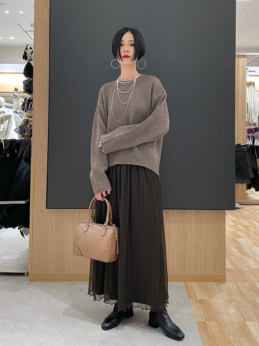 ベージュ系のボストンバッグ、ブラック系のブーツ、シルバー系のネックレスを着用したレディースの冬コーディネートの6枚目の写真