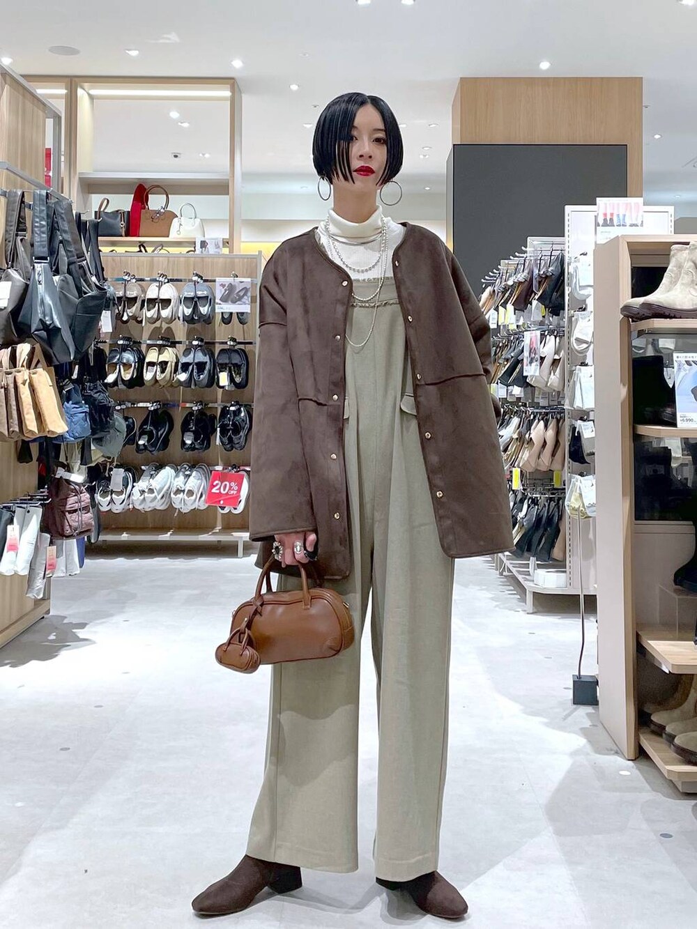 ブラウン系のハンドバッグ、ベージュ系のサロペット/オーバーオール、ホワイト系のニット/セーターを着用したレディースの秋コーディネートの4枚目の写真