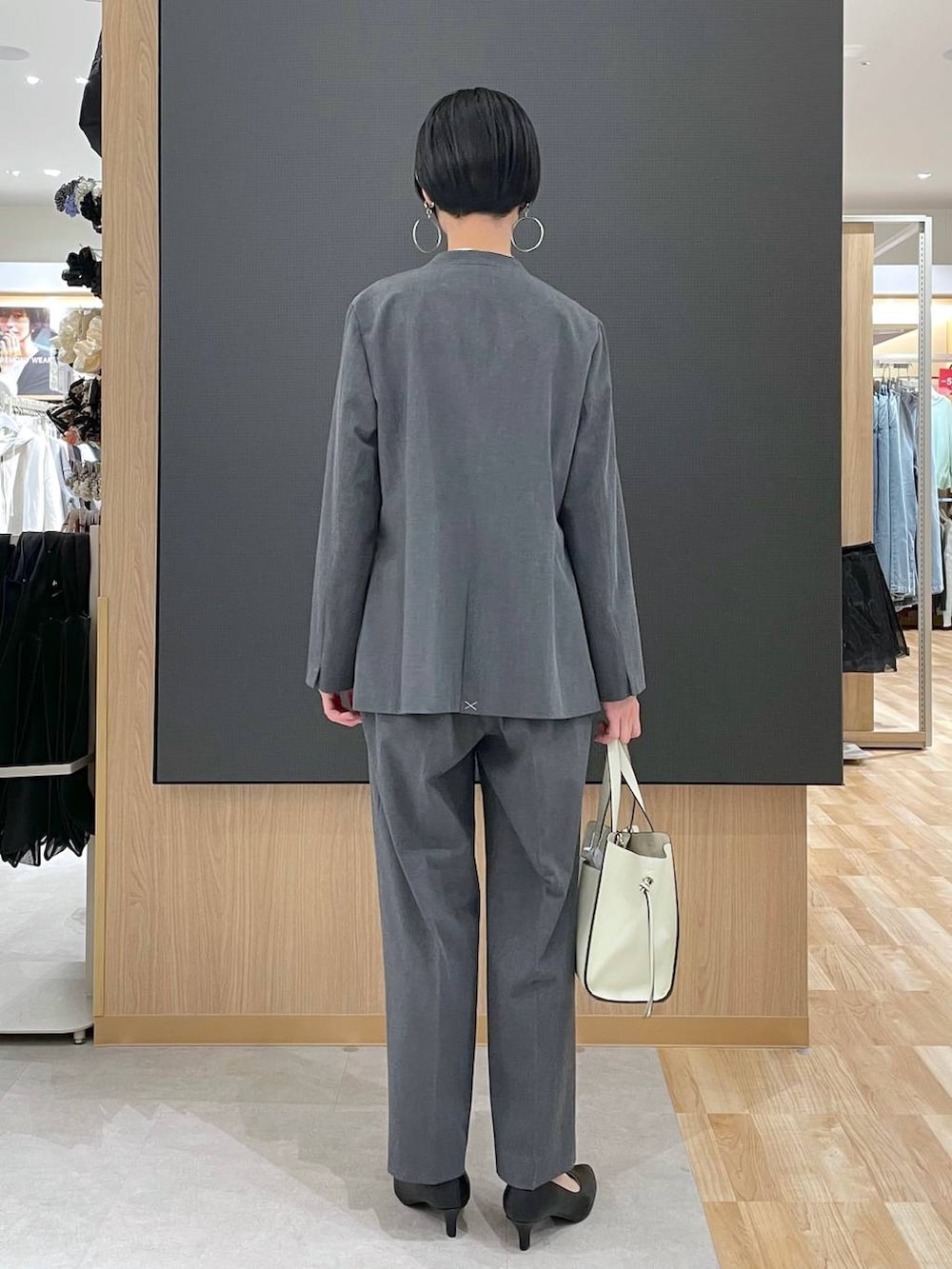 ホワイト系のショルダーバッグ、ブラック系のパンプス、グレー系のスラックスを着用したレディースの冬コーディネートの4枚目の写真