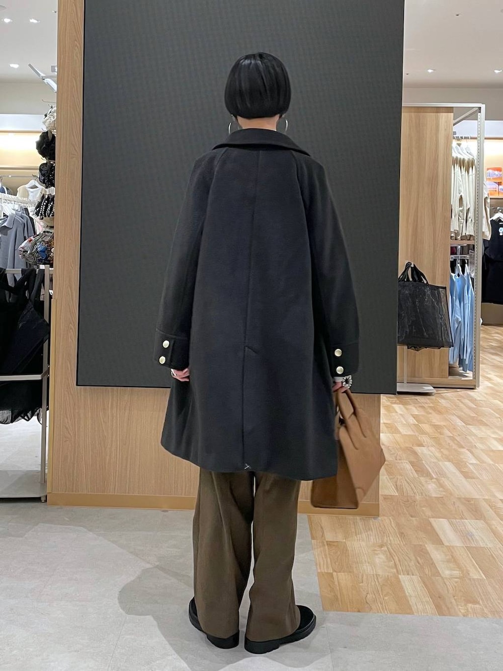 ブラック系のチェスターコート、ホワイト系のニット/セーター、ブラウン系のその他パンツを着用したレディースの冬コーディネートの3枚目の写真