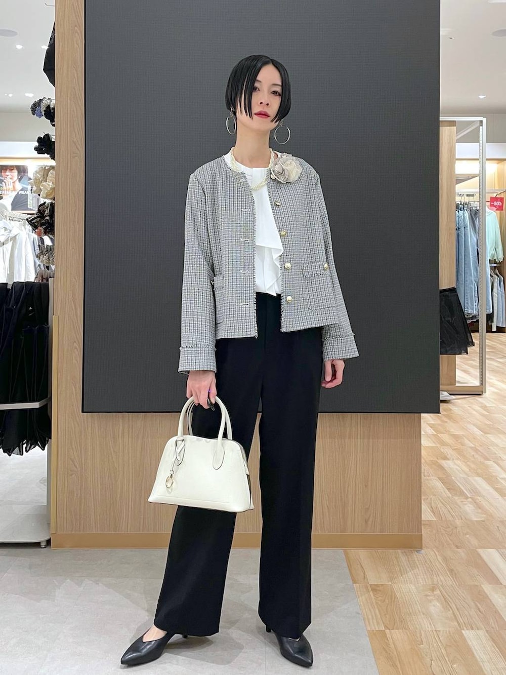 ホワイト系のショルダーバッグ、ブラック系のパンプス、ブラック系のスラックスを着用したレディースの冬コーディネートの7枚目の写真