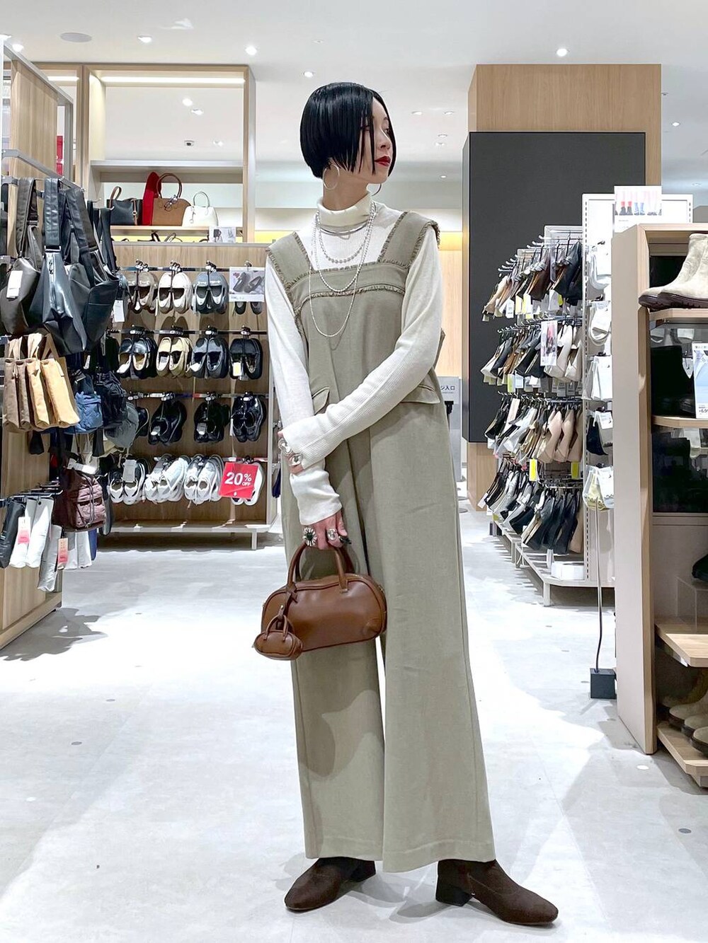 ブラウン系のハンドバッグ、ベージュ系のサロペット/オーバーオール、ホワイト系のニット/セーターを着用したレディースの秋コーディネートの8枚目の写真
