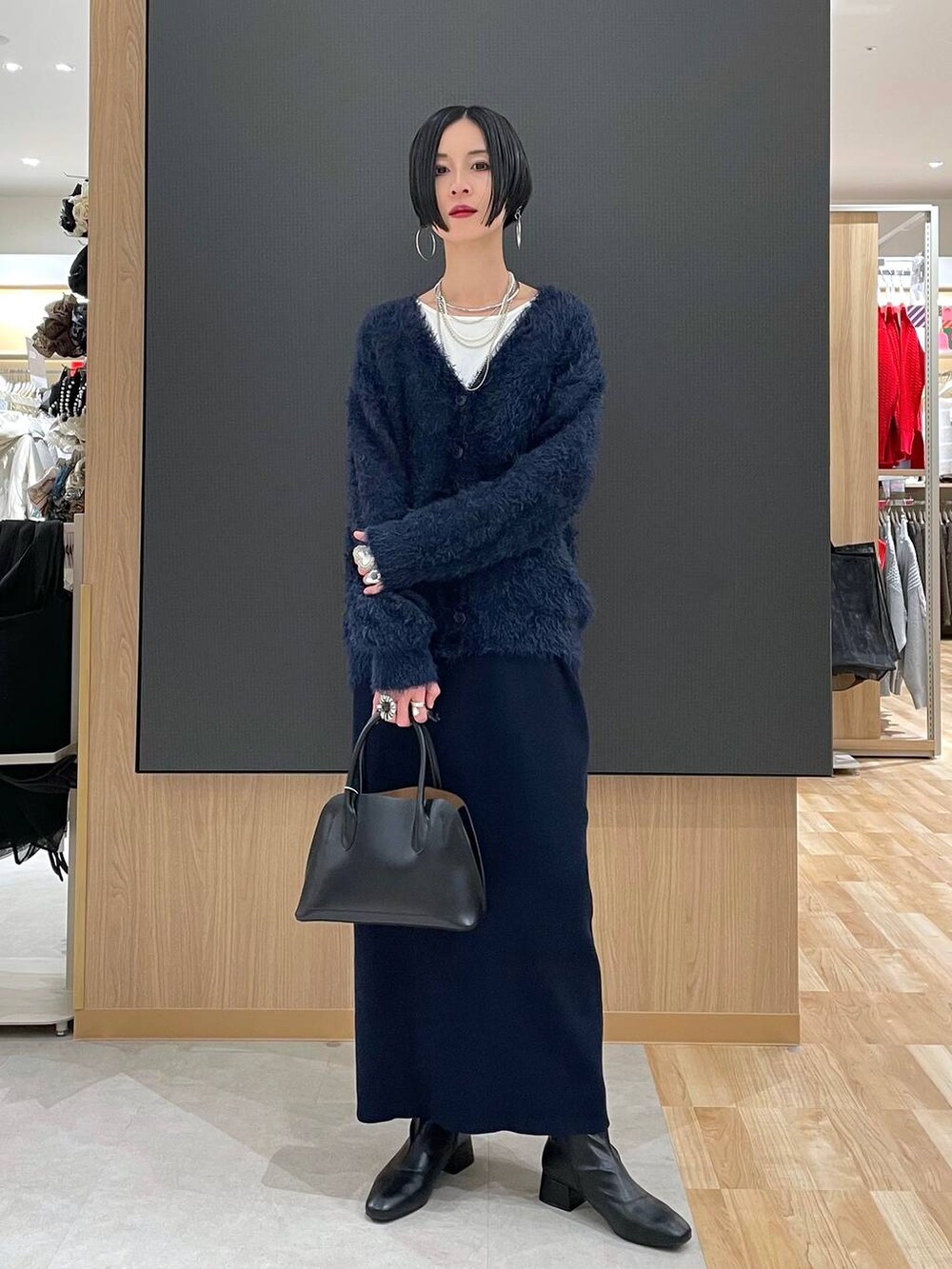 ブラック系のショルダーバッグ、ブルー系のワンピース、ブラック系のブーツを着用したレディースの冬コーディネートの7枚目の写真