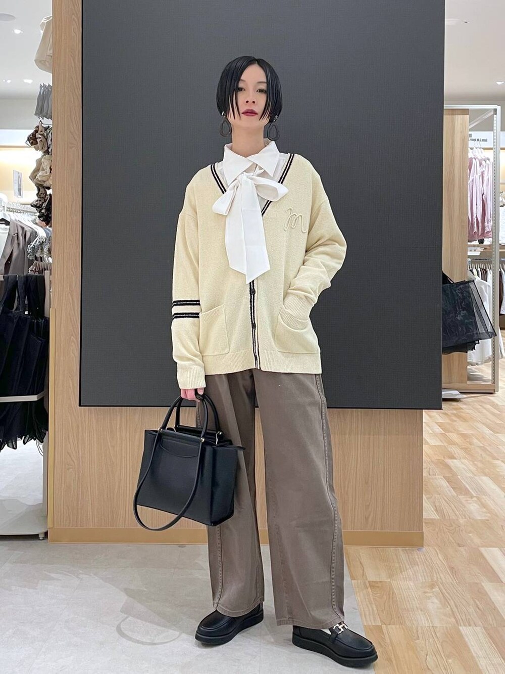 ブラック系のローファー、ブラック系のトートバッグ、ブラウン系のデニムパンツを着用したレディースの春コーディネートの6枚目の写真