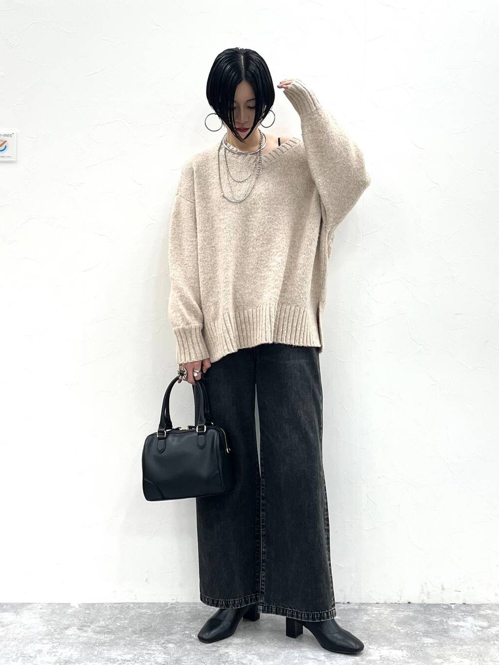 ブラック系のデニムパンツ、ブラック系のボストンバッグ、ブラック系のブーツを着用したレディースの冬コーディネートの2枚目の写真