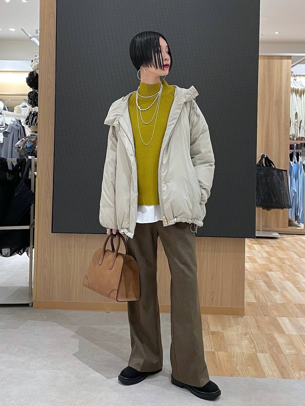 ベージュ系のダウンジャケット/コート、ブラウン系のその他パンツ、ベージュ系のショルダーバッグを着用したレディースの冬コーディネートの2枚目の写真