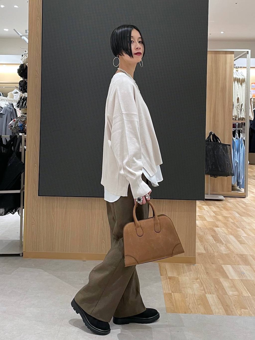 ブラック系のチェスターコート、ホワイト系のニット/セーター、ブラウン系のその他パンツを着用したレディースの冬コーディネートの7枚目の写真