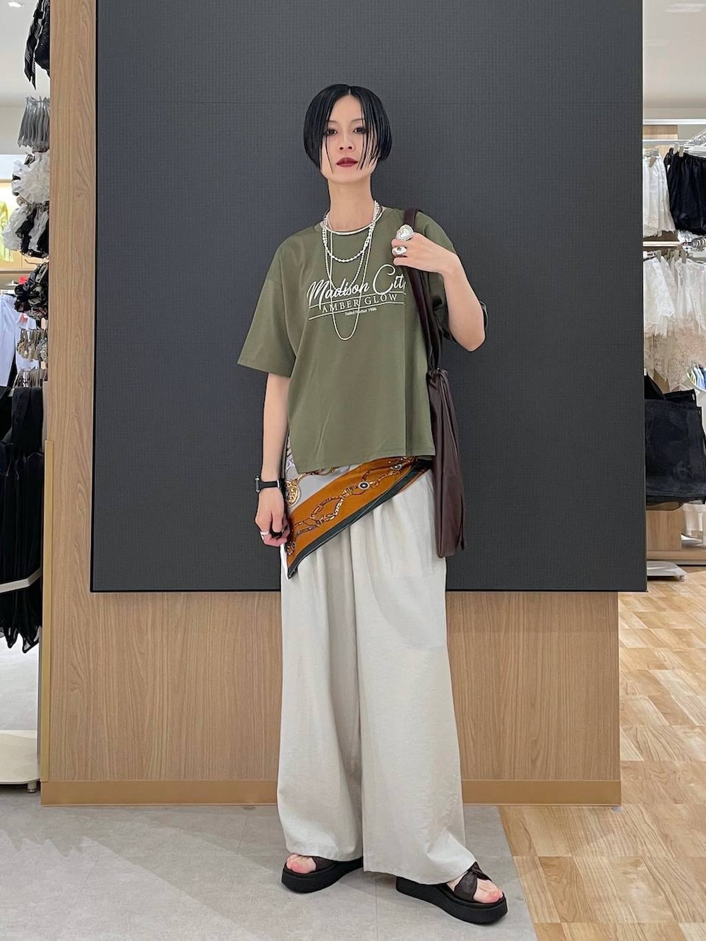ベージュ系のその他パンツ、グリーン系のTシャツ/カットソー、ブラウン系のサンダルを着用したレディースの夏コーディネートの2枚目の写真