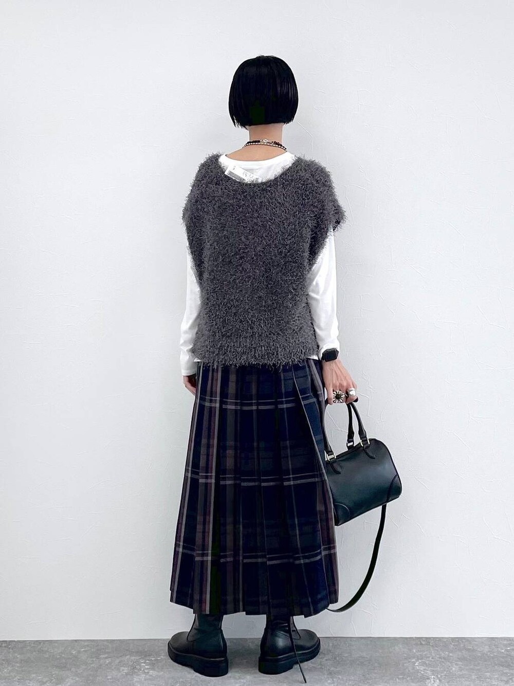 ブラック系のブーツ、グレー系のベスト、ブルー系のスカートを着用したレディースの秋コーディネートの4枚目の写真