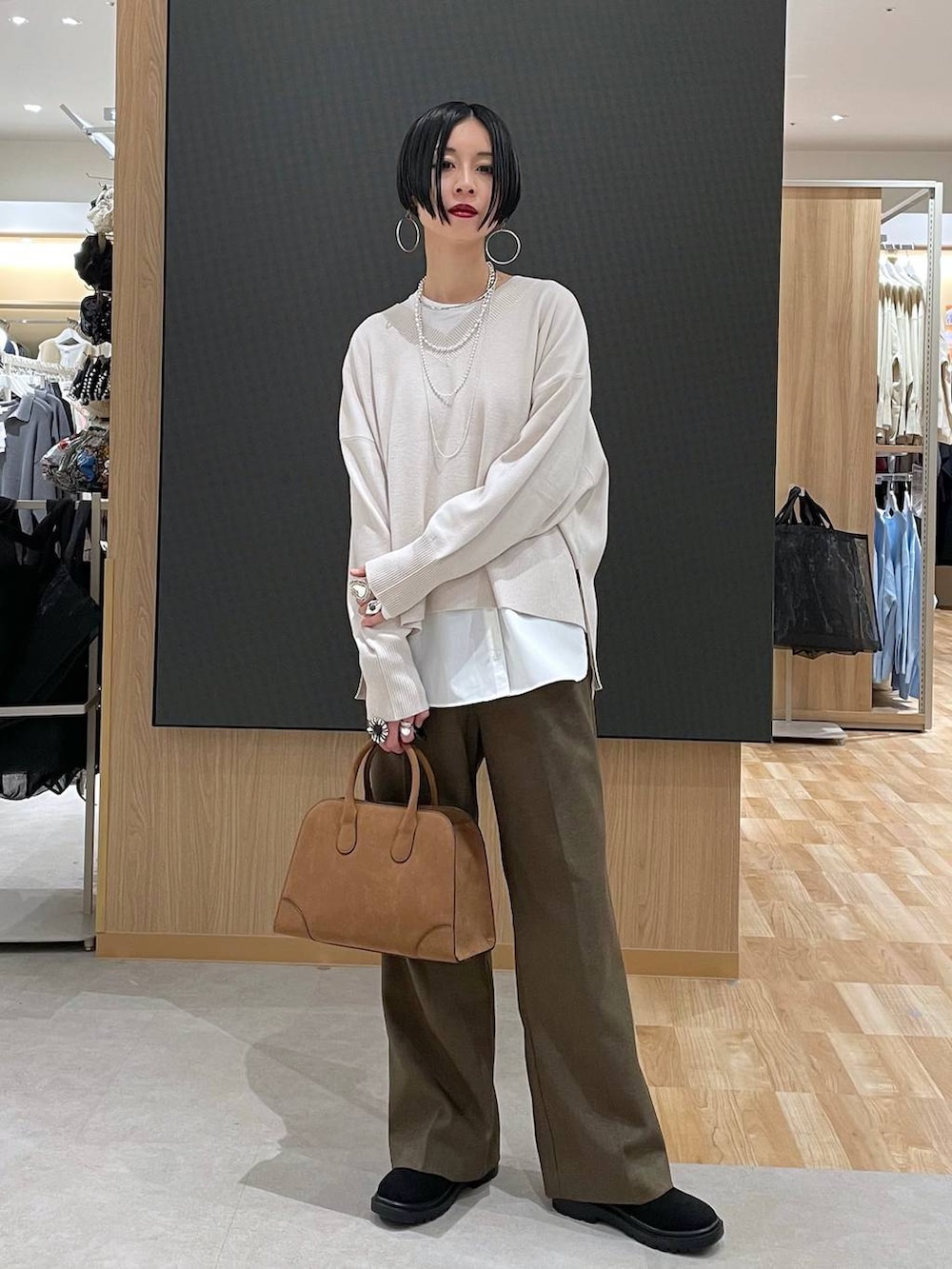 ブラック系のチェスターコート、ホワイト系のニット/セーター、ブラウン系のその他パンツを着用したレディースの冬コーディネートの9枚目の写真