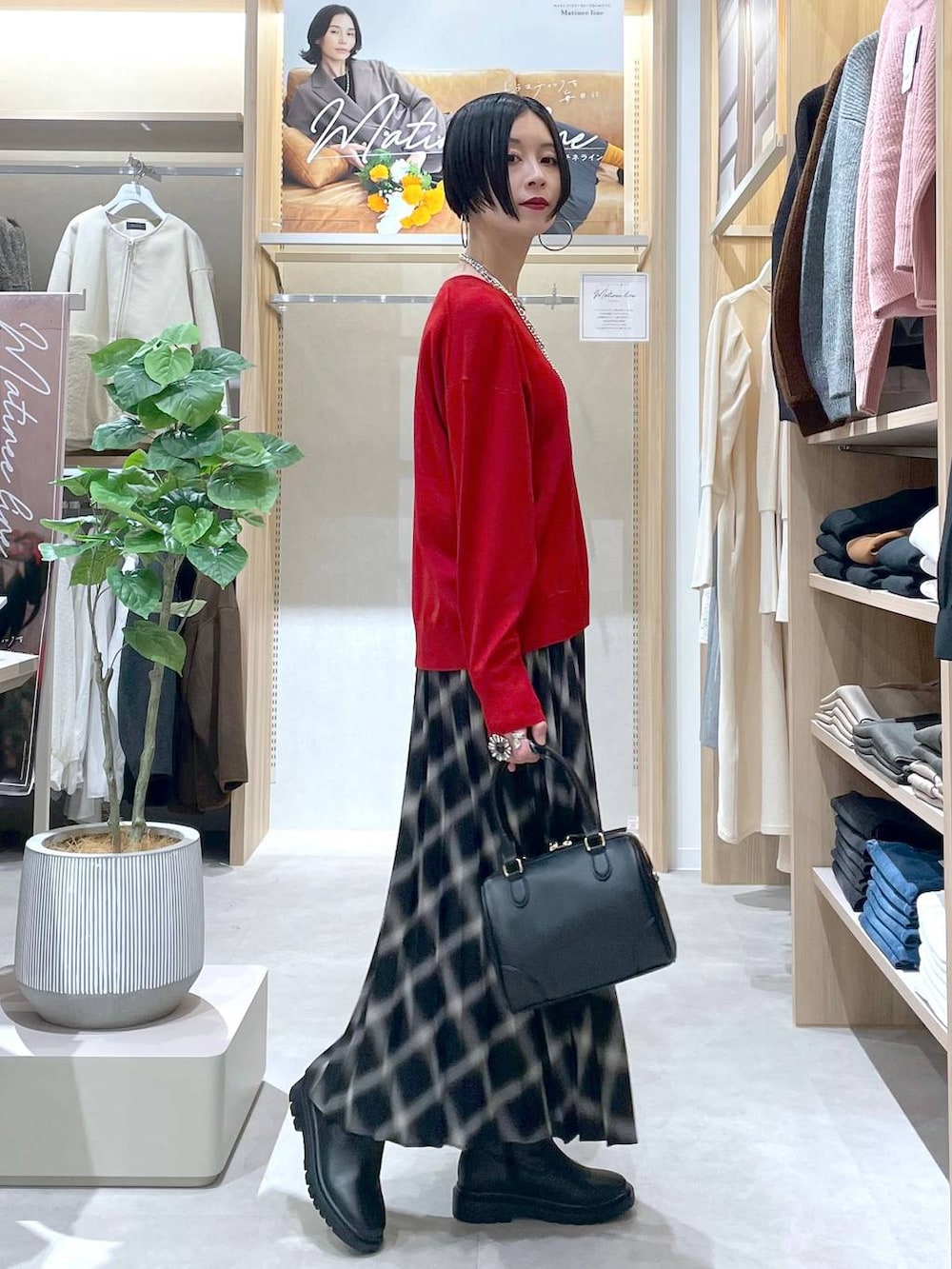 ホワイト系のブルゾン、ブラック系のブーツ、レッド系のニット/セーターを着用したレディースの秋コーディネートの6枚目の写真