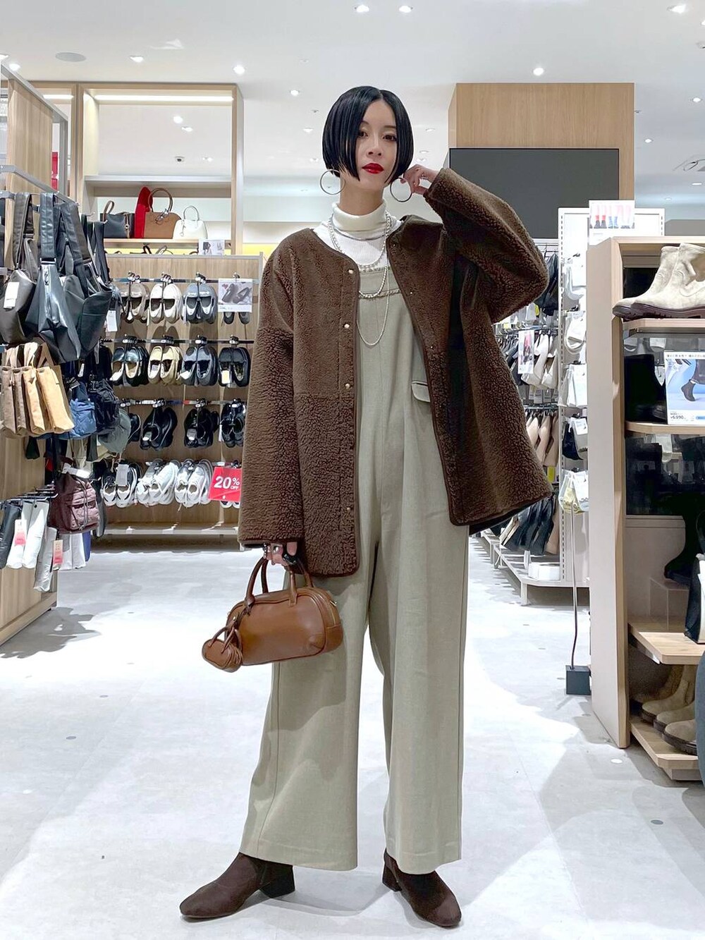ブラウン系のハンドバッグ、ベージュ系のサロペット/オーバーオール、ホワイト系のニット/セーターを着用したレディースの秋コーディネートの5枚目の写真