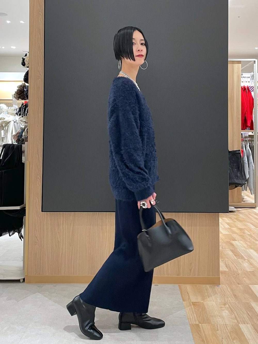 ブラック系のショルダーバッグ、ブルー系のワンピース、ブラック系のブーツを着用したレディースの冬コーディネートの8枚目の写真