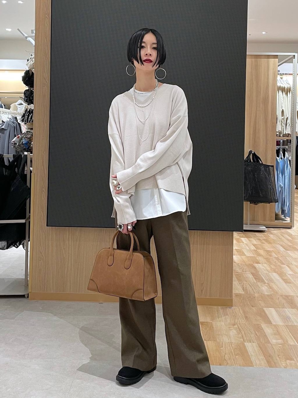 ブラック系のチェスターコート、ホワイト系のニット/セーター、ブラウン系のその他パンツを着用したレディースの冬コーディネートの6枚目の写真