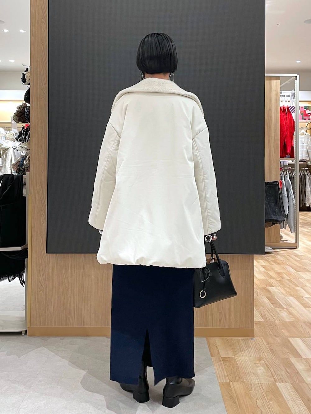 ブラック系のショルダーバッグ、ブルー系のワンピース、ブラック系のブーツを着用したレディースの冬コーディネートの4枚目の写真