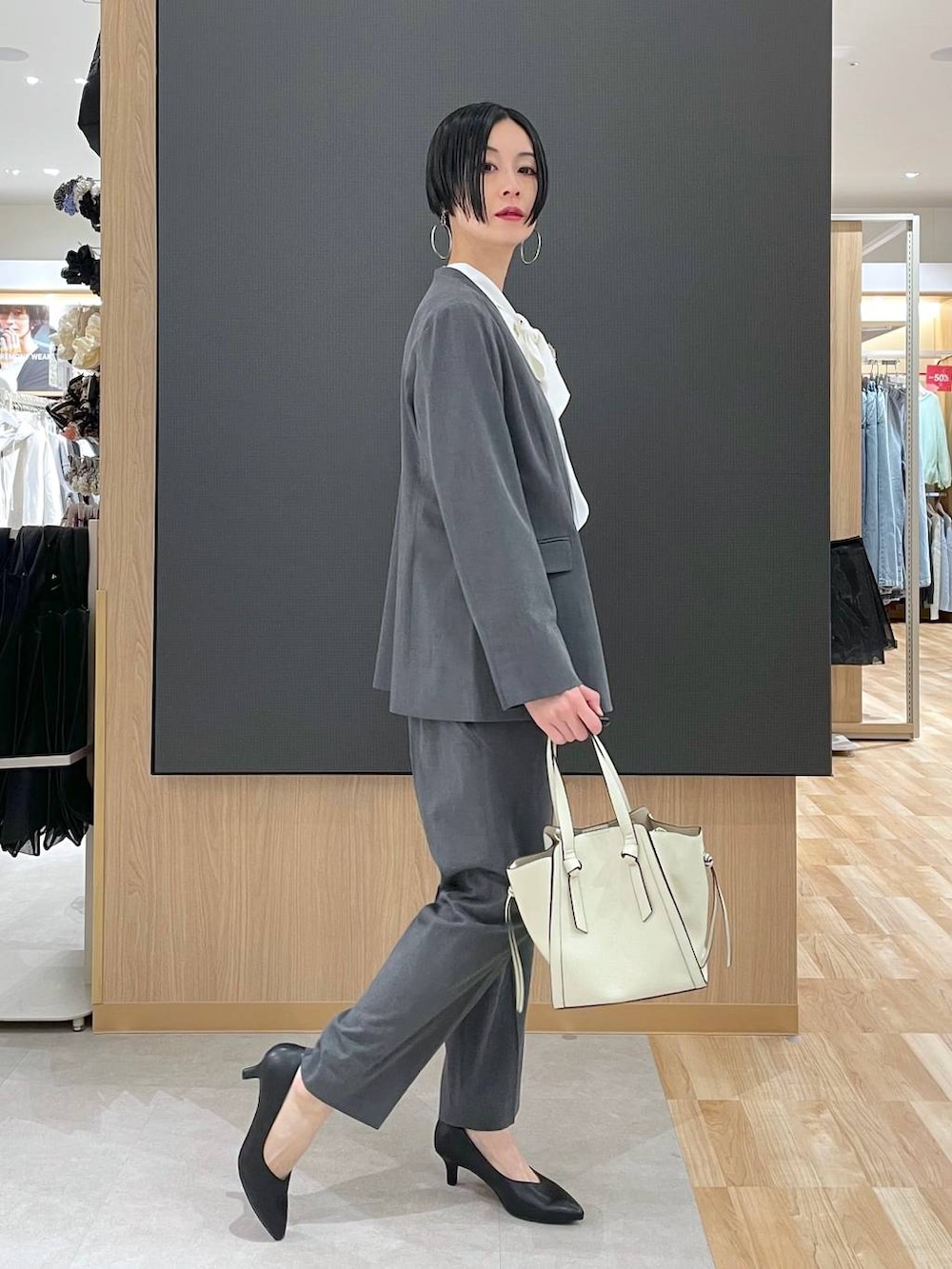 ホワイト系のショルダーバッグ、ブラック系のパンプス、グレー系のスラックスを着用したレディースの冬コーディネートの3枚目の写真