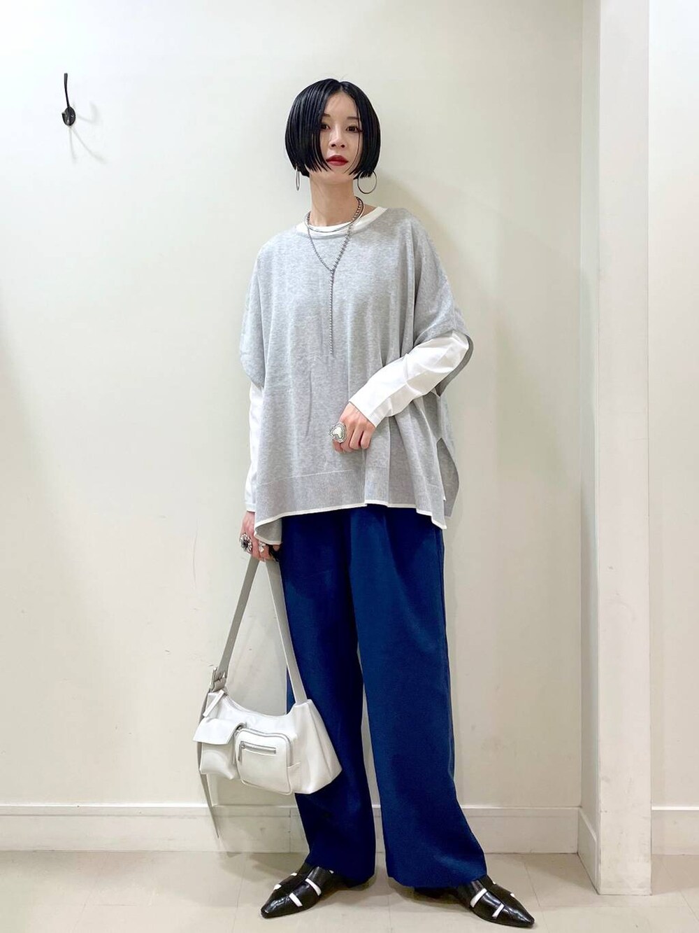 ホワイト系のショルダーバッグ、ホワイト系のTシャツ/カットソー、グレー系のニット/セーターを着用したレディースの春コーディネートの2枚目の写真