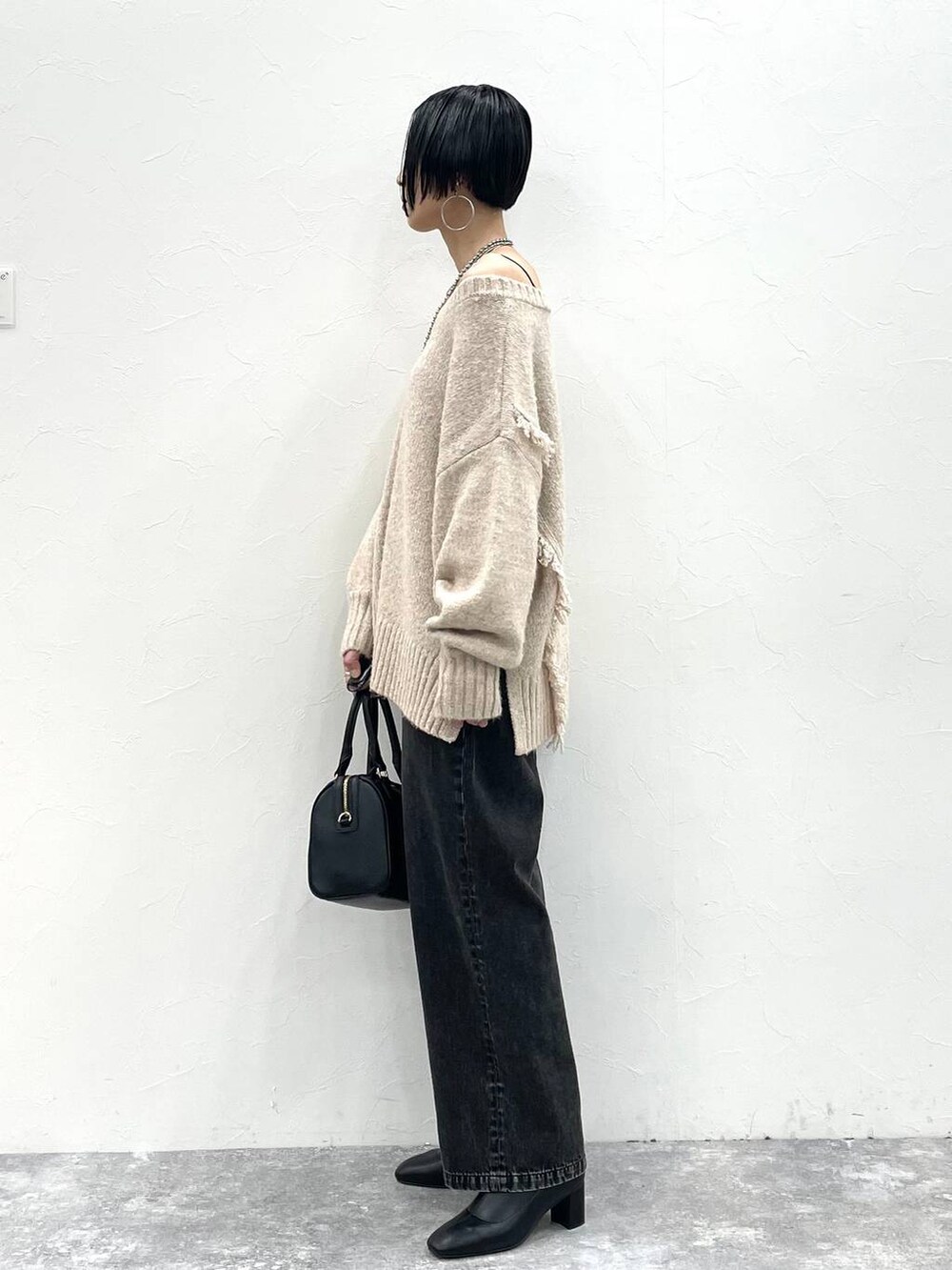 ブラック系のデニムパンツ、ブラック系のボストンバッグ、ブラック系のブーツを着用したレディースの冬コーディネートの5枚目の写真