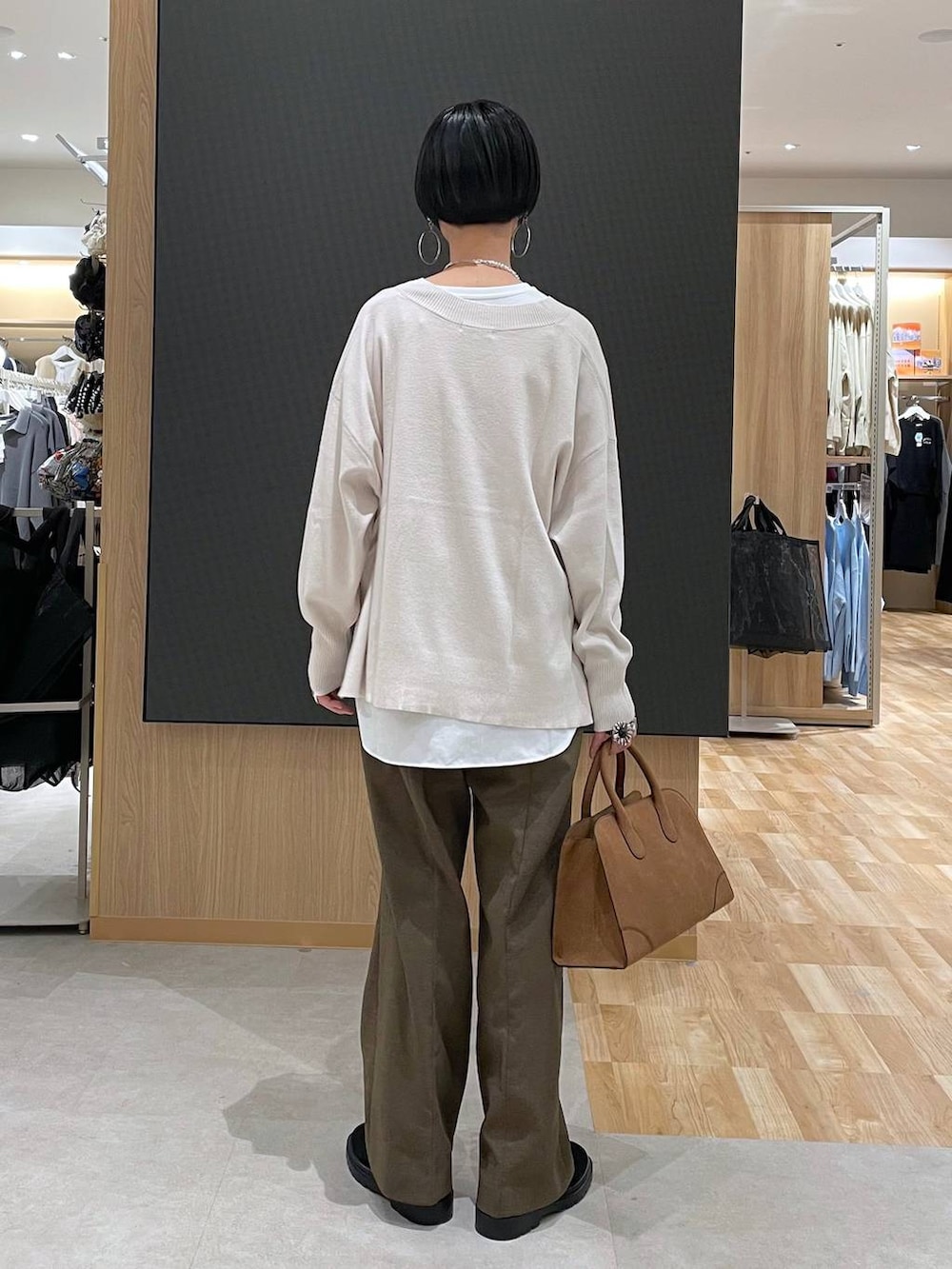 ブラック系のチェスターコート、ホワイト系のニット/セーター、ブラウン系のその他パンツを着用したレディースの冬コーディネートの8枚目の写真