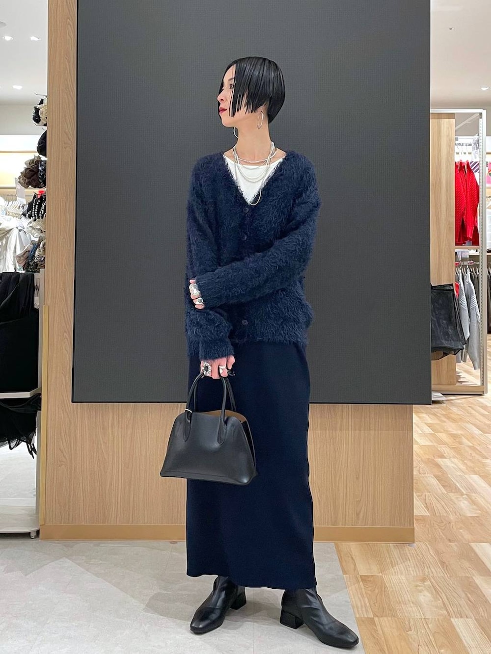 ブラック系のショルダーバッグ、ブルー系のワンピース、ブラック系のブーツを着用したレディースの冬コーディネートの6枚目の写真