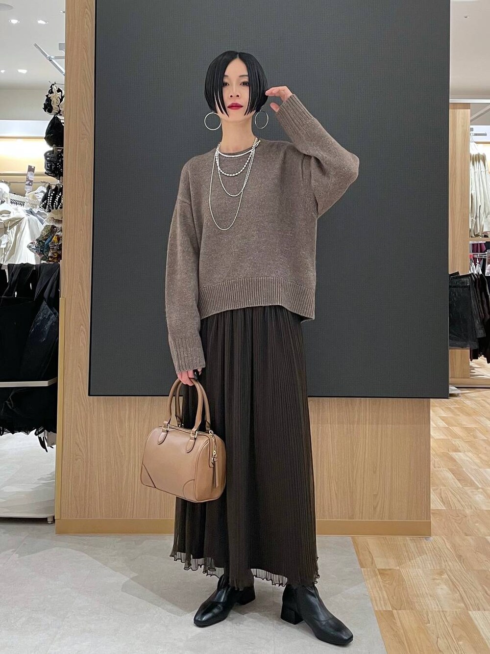 ベージュ系のボストンバッグ、ブラック系のブーツ、シルバー系のネックレスを着用したレディースの冬コーディネートの7枚目の写真