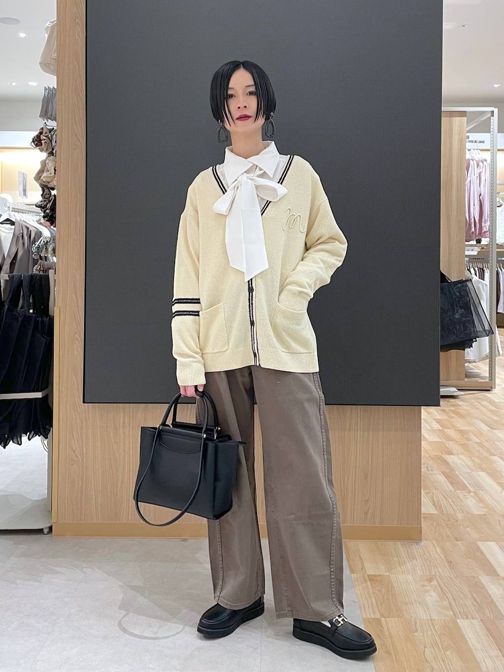 ブラック系のローファー、ブラック系のトートバッグ、ブラウン系のデニムパンツを着用したレディースの春コーディネートの2枚目の写真